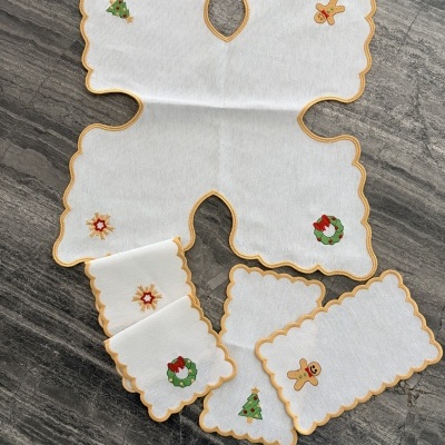 Toalhetes brancos com bordas amarelas e bordados de Natal em superfície cinza