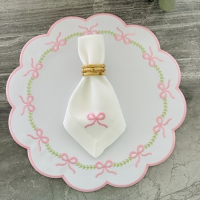 Jogo de mesa com individual branco bordado de laços cor-de-rosa e folhas verdes, toalhete branco com bordado cor-de-rosa e argola de guardanapo natural