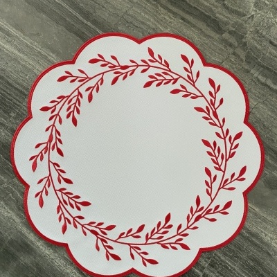 Individual de mesa branco com ramos vermelhos e borda em pétalas sobre pedra cinzenta