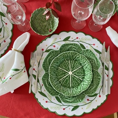 Conjunto de loiça verde com padrão de folhas e toalha vermelha.