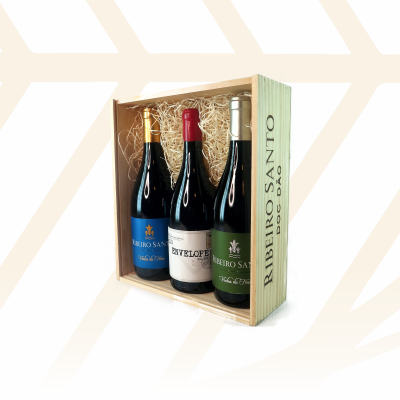 Caixa de madeira com três garrafas de vinho tinto e palha decorativa