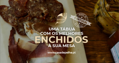 tábuas com enchidos variados sobre mesa de madeira com frasco de conserva ao lado