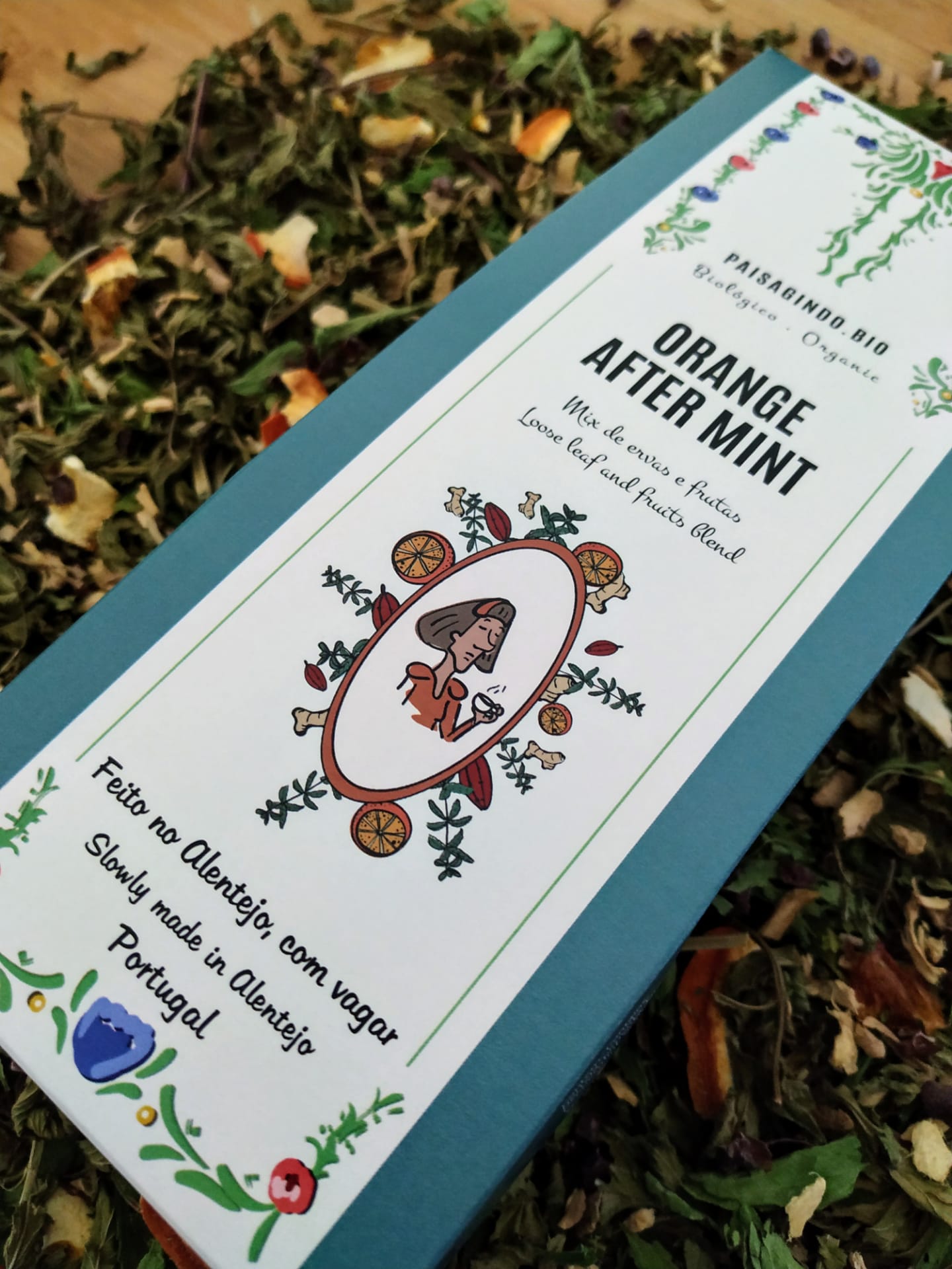 Embalagem de chá 'Orange After Mint' com ilustrações florais e texto bilíngue sobre ervas secas