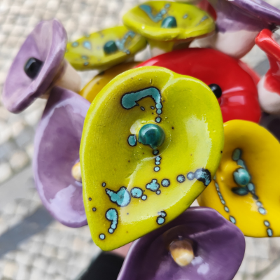 Flores cerâmicas coloridas amarelas, vermelhas e roxas com detalhes azuis e pretos