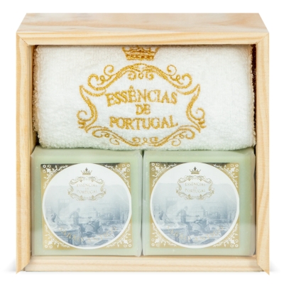 Conjunto de duas velas e uma toalha branca numa caixa de madeira clara.