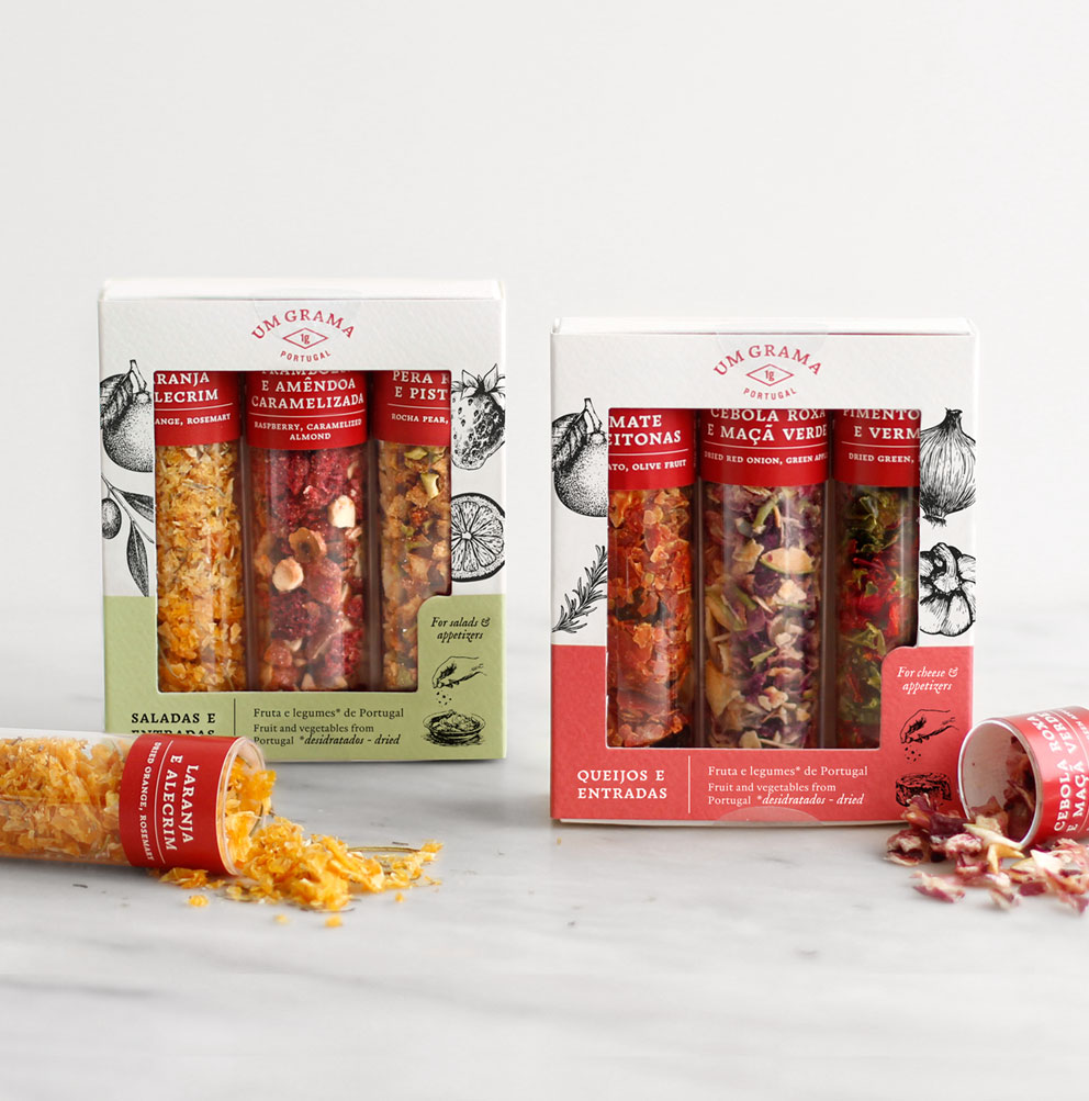 Embalagens de snacks variados em tubos transparentes dentro de caixas brancas com decorações vermelhas