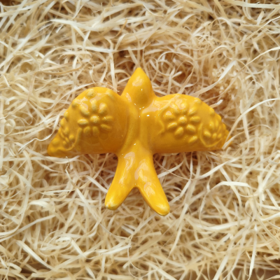 Peça decorativa amarela em cerâmica em forma de pássaro sobre palha