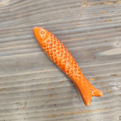 Peixe decorativo em cerâmica laranja sobre madeira clara