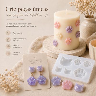 Vela decorativa com pegadas coloridas, brincos lilás em forma de gato e molde para fazer formas, flores secas ao fundo.