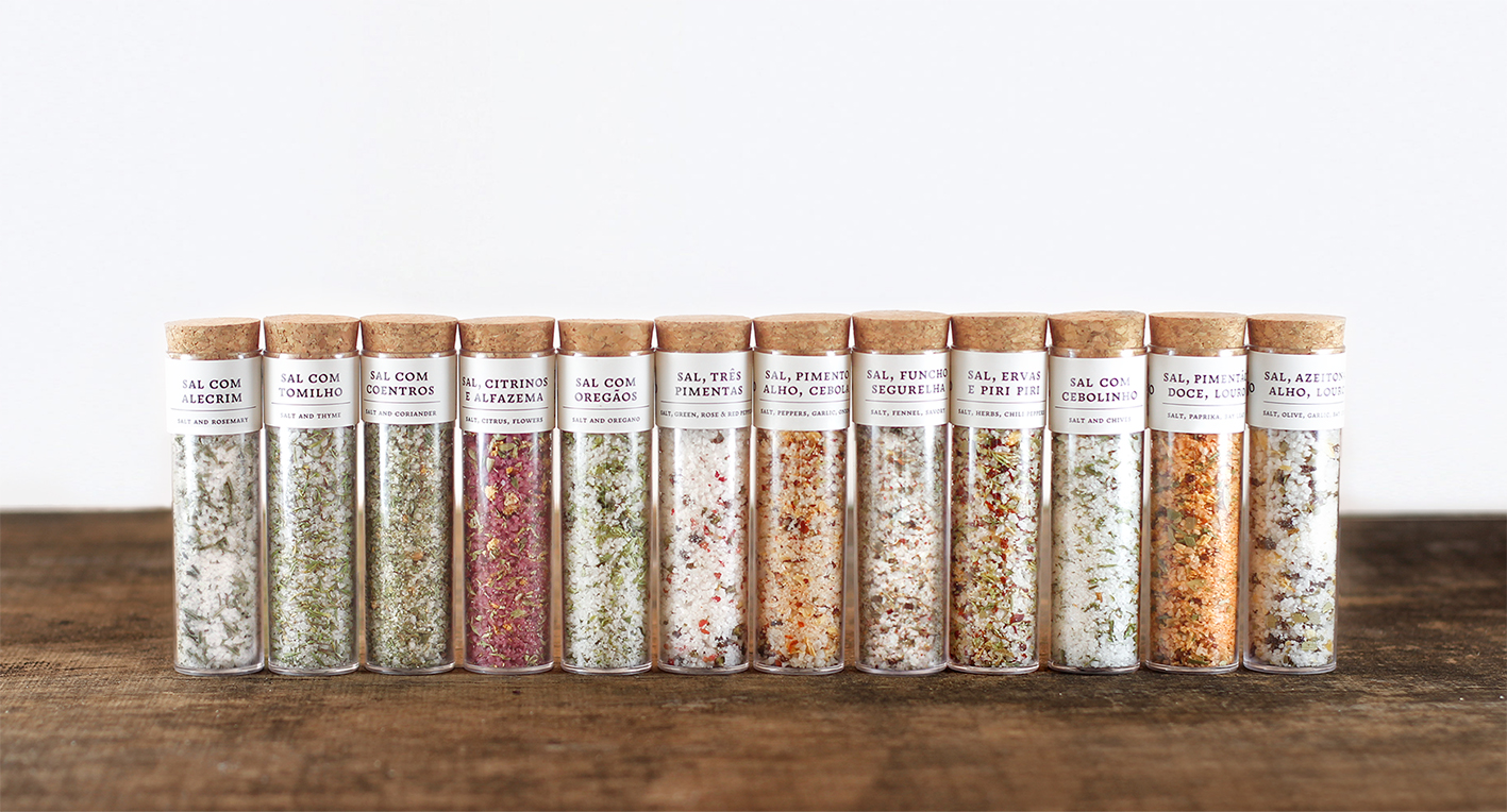 Frascos de vidro com temperos variados em linha sobre mesa de madeira