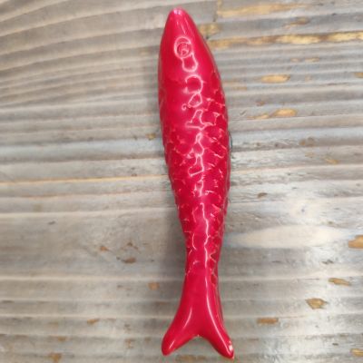 Figura decorativa vermelha em forma de peixe sobre madeira clara