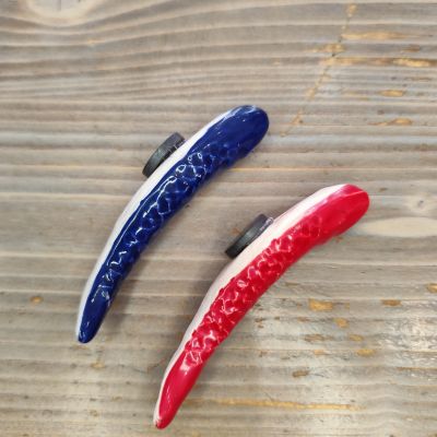 Dois grampos de cabelo coloridos com textura ondulada sobre madeira