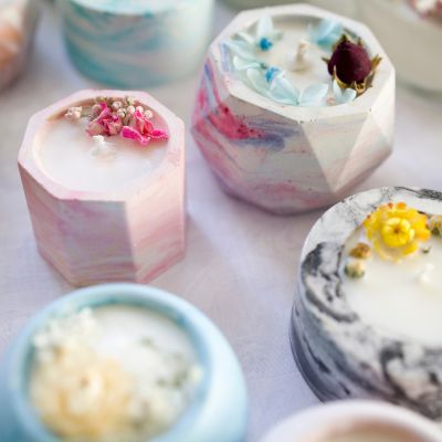 Velas artesanais em recipientes de cerâmica com flores secas no topo