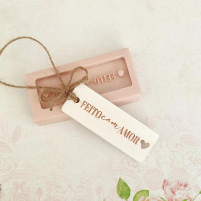 Sabonete rosa com etiqueta 'FEITO com AMOR' e fundo decorativo floral