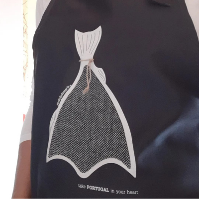 Avental preto com estampa de cauda de peixe e texto associativo a Portugal