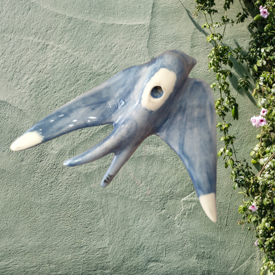 Máscara decorativa azul de animal marinho pendurada numa parede verde