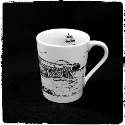 Caneca branca com desenho preto de paisagem com casa e árvores