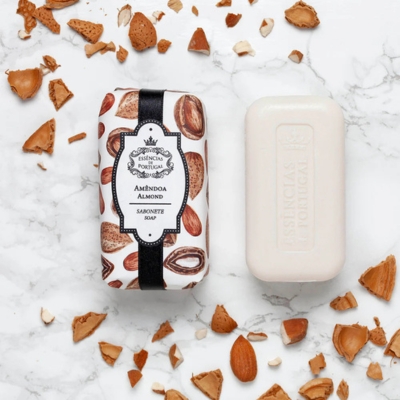 Sabonete Amêndoa com embalagem ilustrada e sabonete branco em fundo branco marmoreado com amêndoas quebradas