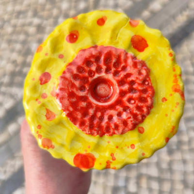 Objeto esférico amarelo com manchas vermelhas e textura central vermelha