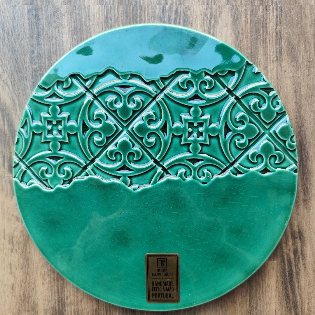 Prato redondo verde com textura e padrão decorativo em relevo e etiqueta dourada