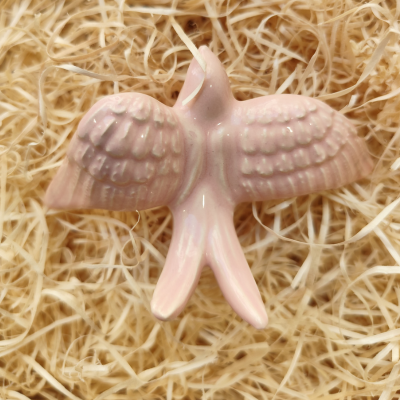 Pássaro decorativo cor-de-rosa em cerâmica sobre palha