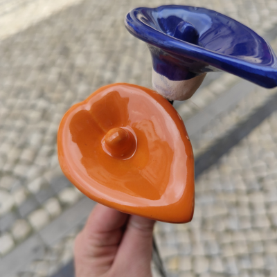 Botões decorativos em cerâmica laranja e azul sobre calçada portuguesa