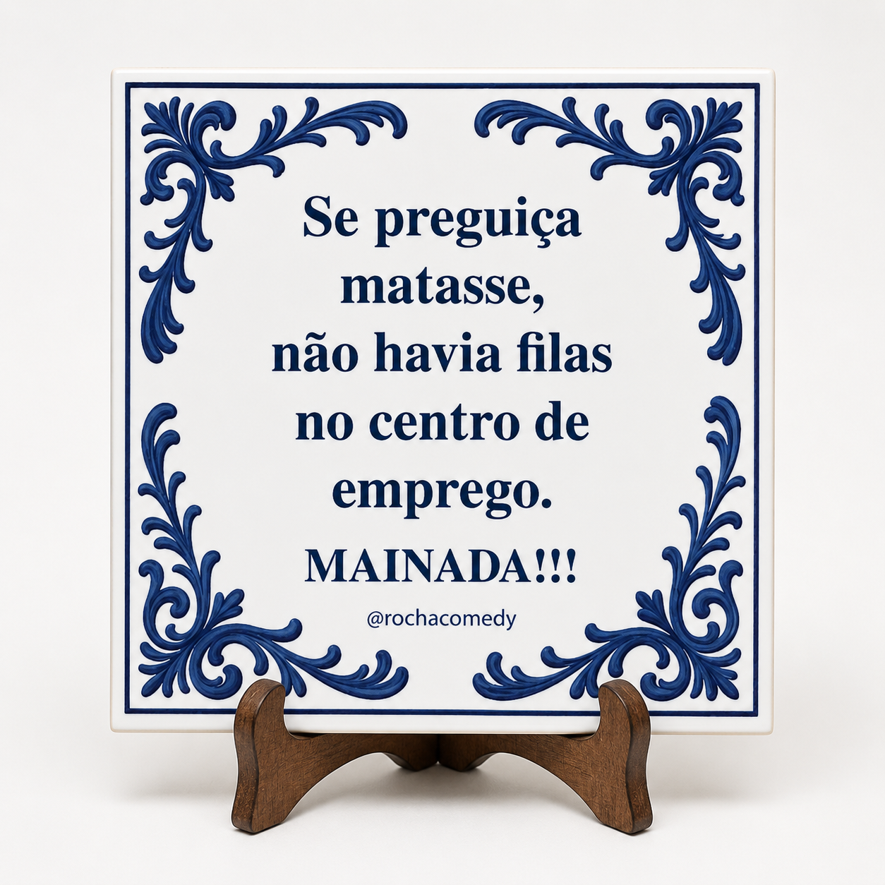 Azulejo branco com moldura azul e texto humorístico em português, exibido num suporte de madeira.