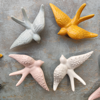 Pássaros decorativos em cerâmica coloridos e texturizados em fundo cinza