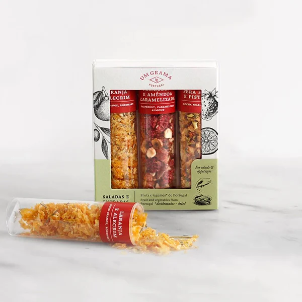 Pack de três snacks variados da marca Um Grama em tubos transparentes dentro de caixa decorada.