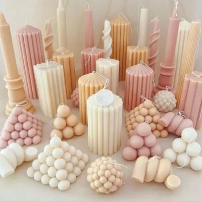 Várias velas decorativas em formatos geométricos e cores suaves