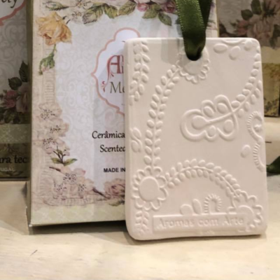 Bloco decorativo em cerâmica branca com relevo floral e texto Aromas com Arte
