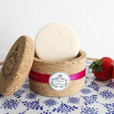 Sabonete redondo branco em caixa de cortiça com fita rosa e morango ao lado