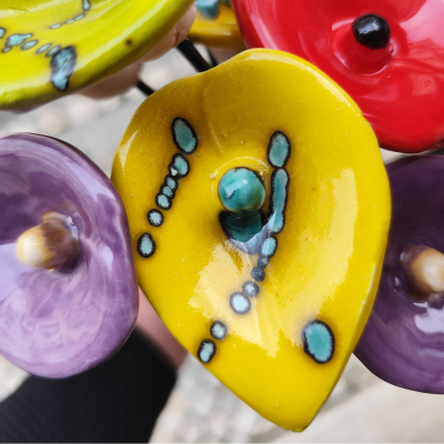 Flores cerâmicas coloridas em amarelo, vermelho e lilás com padrões azuis e pretos