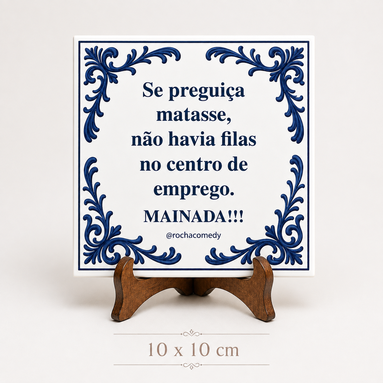 Azulejo branco quadrado decorado com ornamentos azuis e texto em português colocado num suporte de madeira