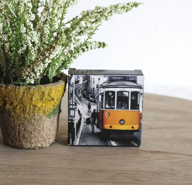 Cubo decorativo com imagem de elétrico amarelo vintage ao lado de vaso com plantas
