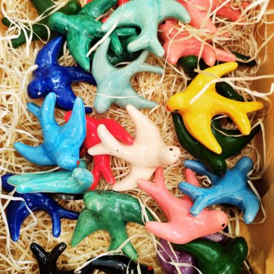 Figuras de pássaros coloridos em cerâmica sobre palha numa caixa
