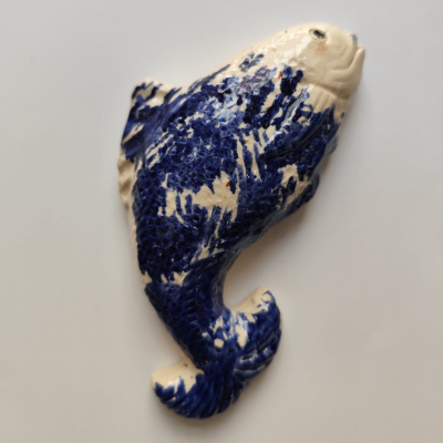 Escultura decorativa de peixe azul e branco com textura rugosa
