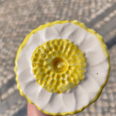 Peça de cerâmica branca com interior amarelo texturizado e pavimento ao fundo