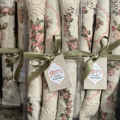 Tecidos florais perfumados enrolados com fita verde e etiqueta Aromas Arte