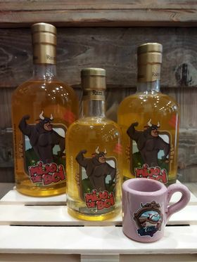 Três garrafas com bebida e rótulo de touro, com caneca rosa à frente