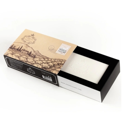 Sabonete branco em caixa preta e bege com ilustração paisagística e selo postal