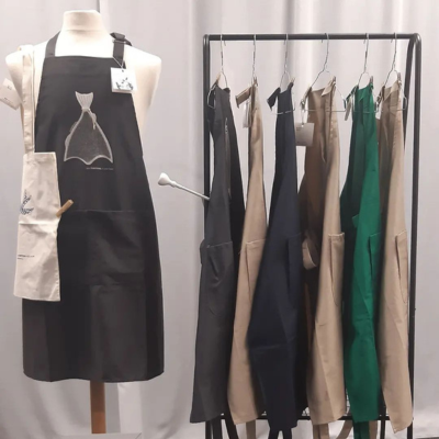 Vários aventais de cores diferentes pendurados num cabideiro e um exposto num manequim