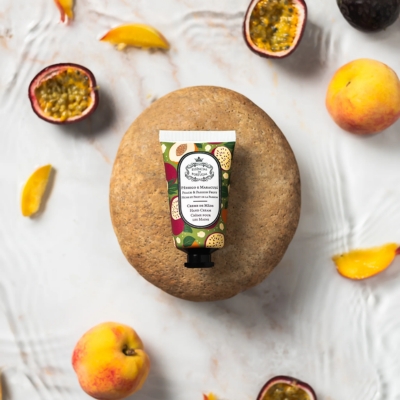 Creme para as mãos com frutas frescas e pedra oval num fundo branco