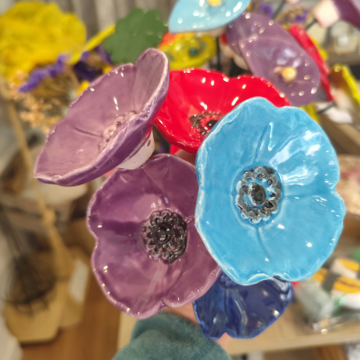 Flores de cerâmica esmaltada coloridas com detalhes pretos em fundo desfocado