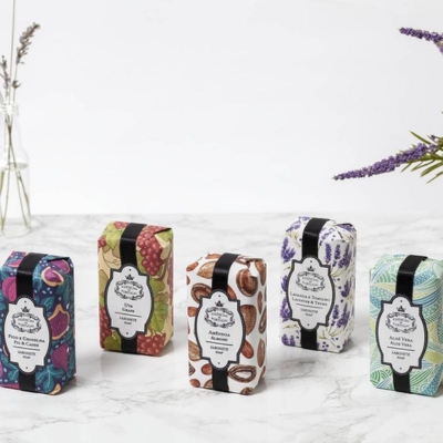 Sabonetes artesanais embalados com padrões coloridos sobre superfície branca marmoreada