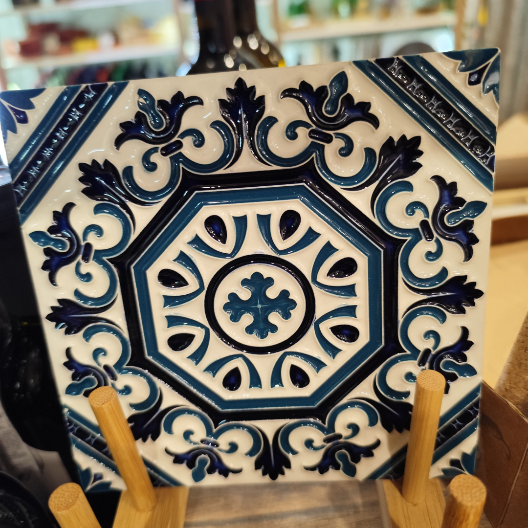 Azulejo cerâmico azul e branco com padrão floral e geométrico em relevo sobre suporte de madeira