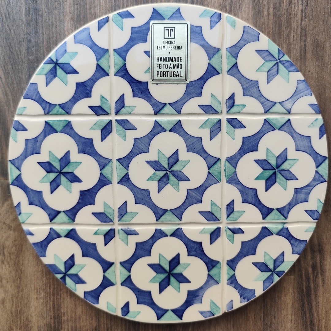 Prato cerâmico redondo com padrão geométrico azul e verde sobre madeira