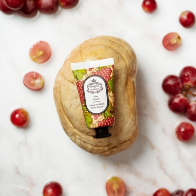 Tubo de creme para as mãos com ilustrações de uvas sobre concha e bagos de uva