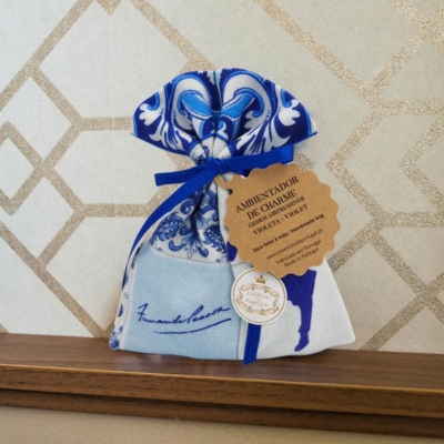 Saco de tecido azul e branco com padrão floral e etiqueta castanha