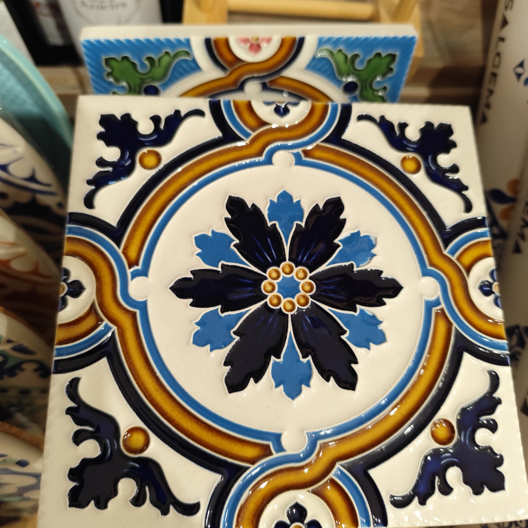 Azulejo cerâmico com padrão floral e geométrico em azul, castanho e verde